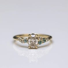 a yellow gold engagement ring with two green and white diamonds