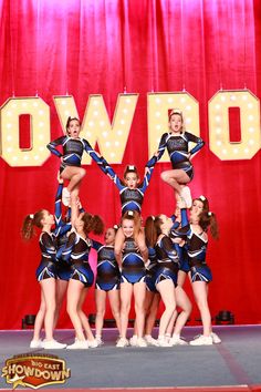 a group of cheerleaders standing on top of each other in front of a sign