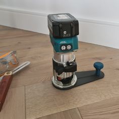 a coffee maker sitting on top of a wooden floor next to some scissors and other tools