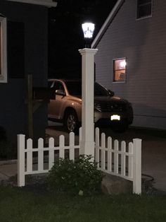 a car is parked in front of a house at night with the light turned on