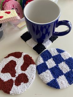 crocheted coasters are sitting on a table next to a cup and mug