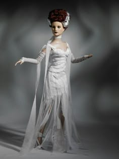 a woman dressed in white is standing with her arms spread out and wearing a long veil