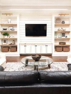 a living room filled with furniture and a flat screen tv mounted on the wall above a glass table