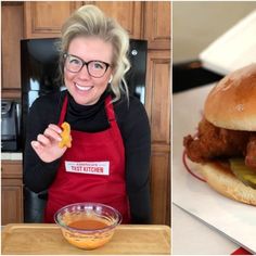 a woman in an apron is holding a pickle and a hamburger on a bun