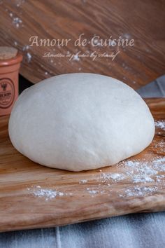 a ball of bread sitting on top of a wooden cutting board