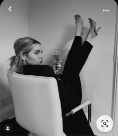 a black and white photo of a woman sitting in a chair with her legs up