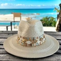 Calling all beach babes and summer queens!   Surf's up for the season with this on-trend panama hat, the perfect accessory to catch some rays and turn heads wherever you go.  This beauty features a classic cream-colored straw hat with a wide brim for maximum sun protection, accented with delicate seashells and gleaming gold chains for a touch of boho chic.  Whether you're strolling along the shoreline or sipping cocktails at a rooftop bar, this hat is sure to add a touch of whimsical flair to yo Beachy Hat For Summer Beach, Beachy Hat For Summer Beach Outings, Summer Hat Bands For Vacation, Flat Brim Panama Hat For Beach Season, Summer Coastal Boater Hat For Beach, Coastal Style Boater Hat For Beach And Summer, Adjustable Hat With Curved Brim For Holidays, Summer Beach Hat With Curved Brim, Flat Brim Hats For Beach Season