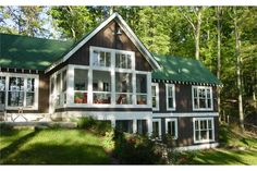 a house in the woods with lots of windows and plants on the front lawn area