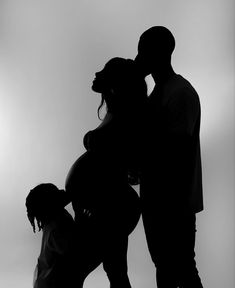 a man and woman standing next to each other with their arms around one another as they kiss