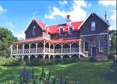 a large house sitting in the middle of a lush green field with lots of flowers