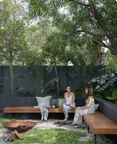 two women sitting on wooden benches in a garden