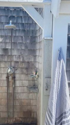 an outdoor shower with two hand held faucets and towels hanging on the wall