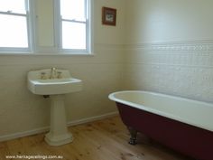 an old fashioned bathtub and pedestal sink in a white bathroom with wood flooring