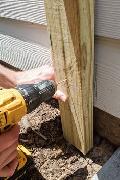 a person using a power drill to attach a piece of wood on the side of a house