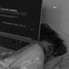 a person laying in bed with their head on the laptop