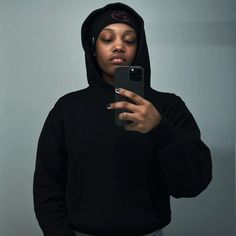 a woman taking a selfie with her cell phone in front of her face while wearing a hoodie