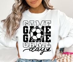 a woman wearing a white sweatshirt with the words game on it and a soccer ball