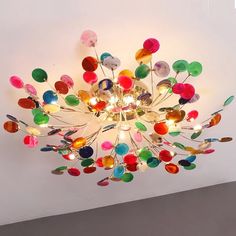 a colorful chandelier hanging from the ceiling in a room with white walls and flooring