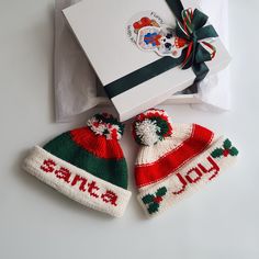 two knitted christmas hats sitting next to a gift box