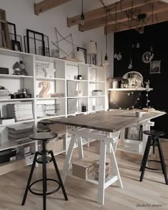 a room filled with lots of white shelves and chairs next to a wooden table in the middle