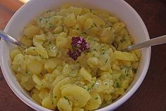 a white bowl filled with macaroni and cheese on top of a wooden table