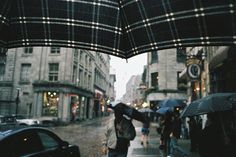 people are walking down the street with umbrellas