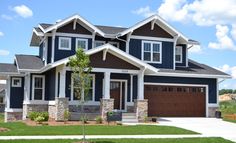 a blue house with white trim and brown garage doors on the front door is shown