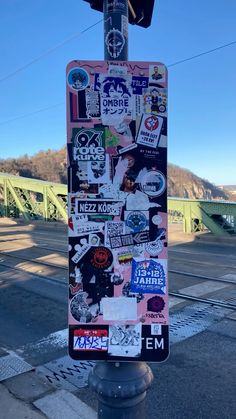 a street sign covered in lots of stickers on the side of it's pole