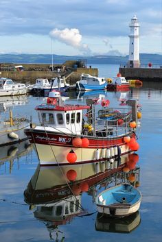 several boats are docked in the water near a lighthouse