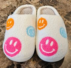 a pair of white slippers with colorful smiley faces painted on the front and sides