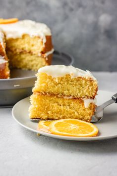 a slice of orange cake with icing on a plate next to the rest of the cake