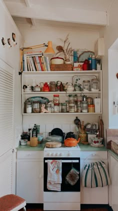 a kitchen with an oven and shelves filled with dishes