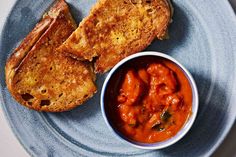 a blue plate topped with two pieces of bread and a bowl of tomato sauce