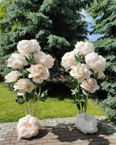 three vases filled with flowers sitting on top of a brick walkway