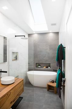 a white bath tub sitting inside of a bathroom next to a wooden dresser and mirror