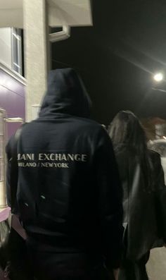 two people walking down the street in front of a building with an exchange sign on it