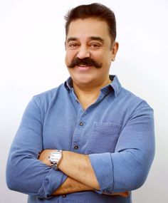 a man with a moustache on his face and arms crossed, wearing a blue shirt