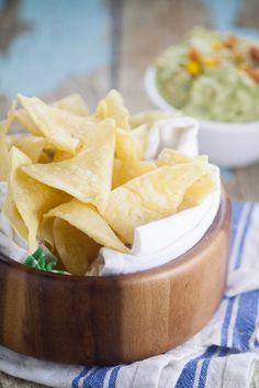 a wooden bowl filled with chips on top of a table