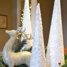 two white christmas trees with glitter deer figurines