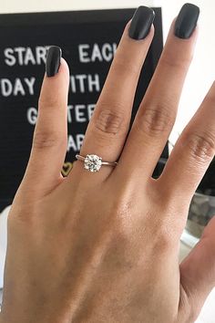 a woman's hand with black nails and a ring on her left hand, next to a sign that says start each day with a date