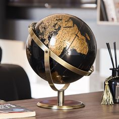 a black and gold globe sitting on top of a table next to a remote control