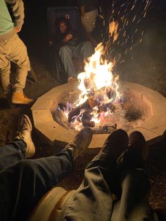 people sitting around a fire pit with their feet up