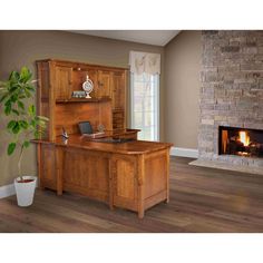 a wooden desk sitting in front of a fireplace with a potted plant next to it