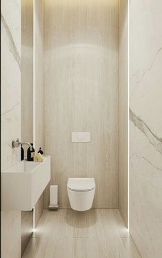 a white toilet sitting inside of a bathroom next to a wall mounted sink and mirror