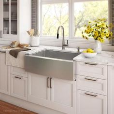 a large kitchen with white cabinets and stainless steel sink in the center, surrounded by yellow flowers