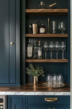 a kitchen with blue cabinets and wine glasses on the counter top in front of it