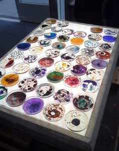 a table covered in lots of different colored glass plates on top of wooden pallets