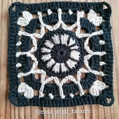 a black and white crocheted square on top of a wooden table