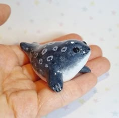 a hand is holding a small toy dolphin