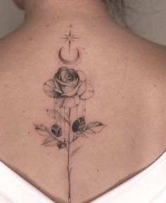 a woman's back with a rose and crescent tattoo on her upper back shoulder